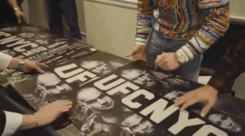 Conor M signing a UFC poster to show martial arts marketing