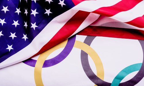 Flag of the United States folded over a flag with the Olympic rings